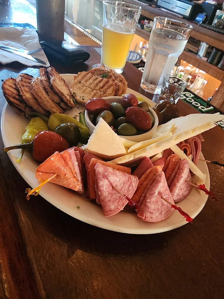An antipasti platter with cured meats, cheeses, olives, fruit and grilled bread