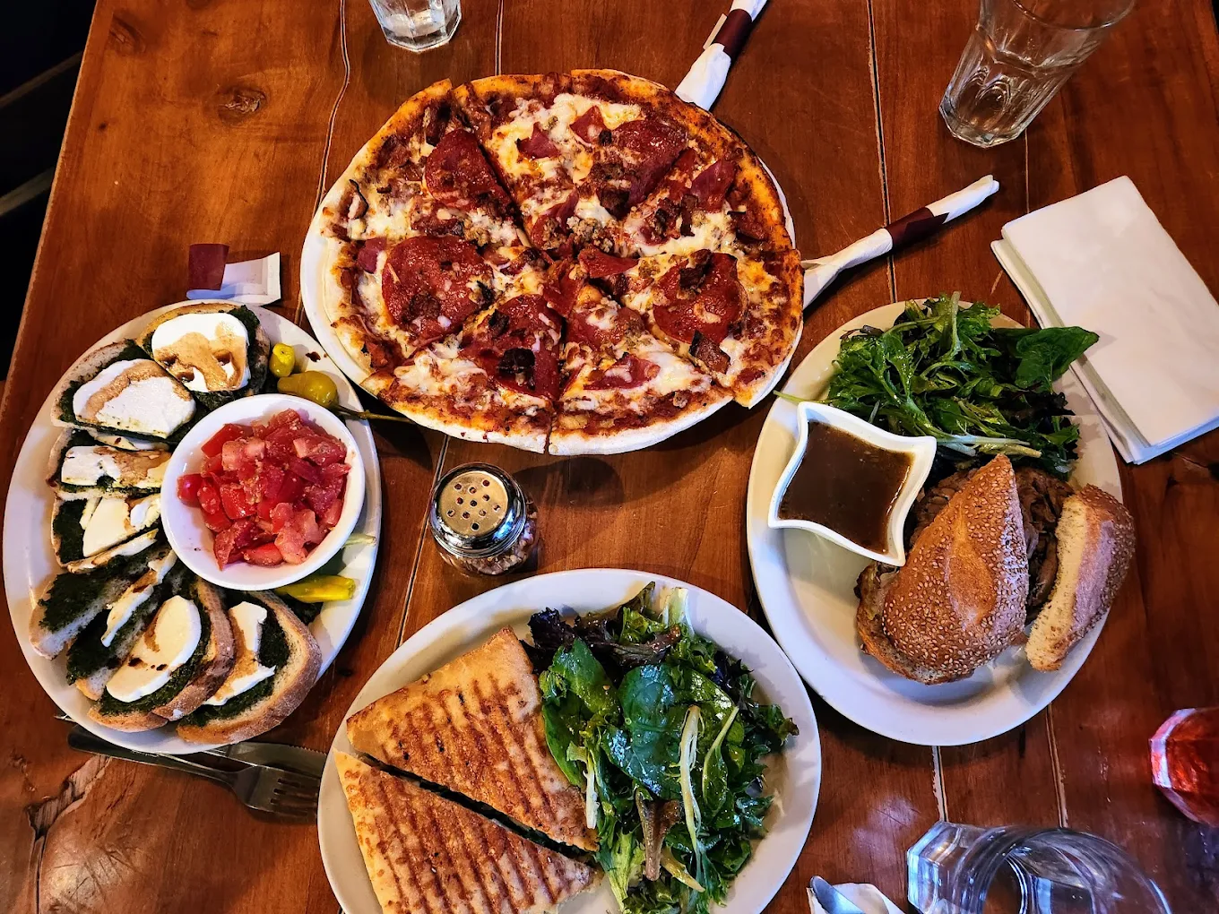 A table at Nessun Dorma filled with pizza, panini, antipasti and greens